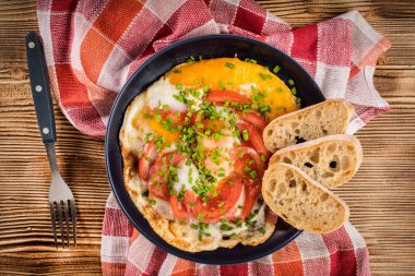 Ev yapımı kahvaltı yumurta ile domates ahşap masa üzerinde kızarmış. Üstten görünüm.