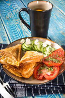 Peynir, domates ve salatalık bir plaka üzerinde sandviç.