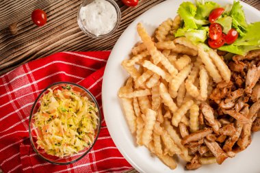 Yunan jiroskopu, patates kızartması ve tabakta salata. Üst görünüm.