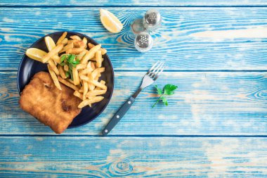 Tabakta patates kızartması olan kızarmış morina balığı. Üst görünüm.