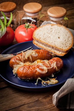 Kızarmış sosis bir tabak içinde soğan ile.