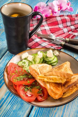 Peynir, domates ve salatalık bir plaka üzerinde sandviç.