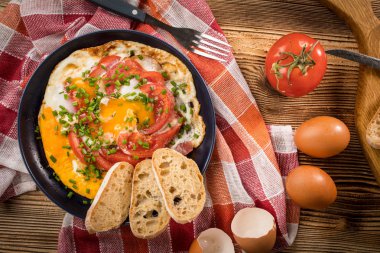 Ev yapımı kahvaltı yumurta ile domates ahşap masa üzerinde kızarmış. Üstten görünüm.