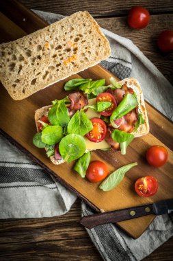 Ciabatta ahşap tahta üzerinde Roka Salatası, pastırma ve sarı peynirli sandviç. Üstten Görünüm.