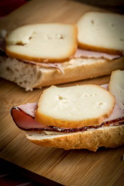 Jambon ve kesme tahtası üzerinde füme peynir sandviç.