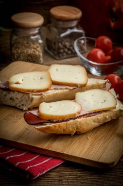 Jambon ve kesme tahtası üzerinde füme peynir sandviç.
