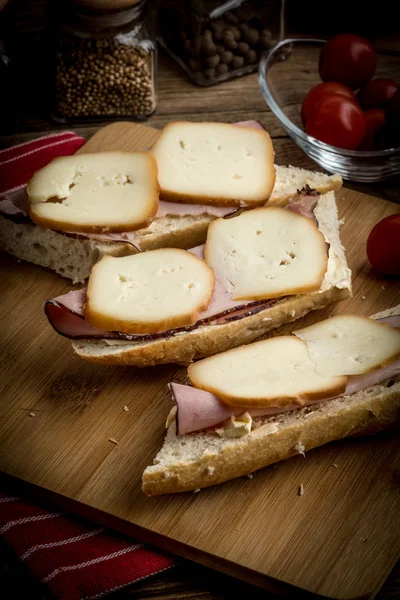 Jambon ve kesme tahtası üzerinde füme peynir sandviç.