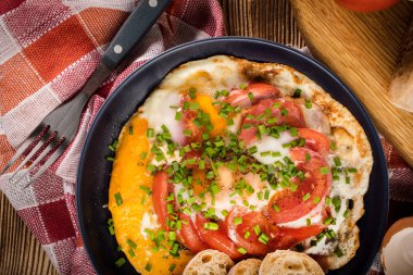 Ev yapımı kahvaltı yumurta ile domates ahşap masa üzerinde kızarmış. Üstten görünüm.