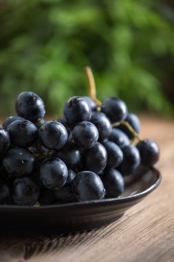 Kara üzüm kase ahşap masa üzerinde. Seçici odak.