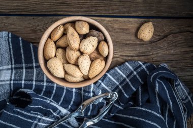 Eski ahşap masa üzerinde ahşap kase kabuu içinde badem.