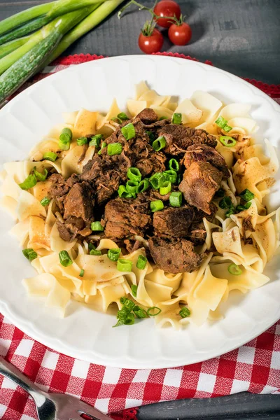 Stewed beef with tagliatelle pasta on plate.