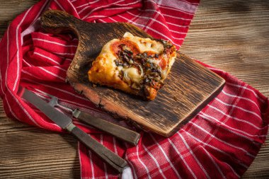 Bir parça kesme tahtası üzerinde ev yapımı pizza.