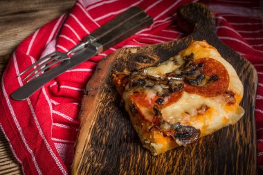 Bir parça kesme tahtası üzerinde ev yapımı pizza.