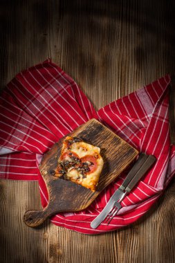 Bir parça kesme tahtası üzerinde ev yapımı pizza.