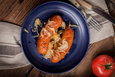 Kızarmış sosis bir tabak içinde soğan ile.