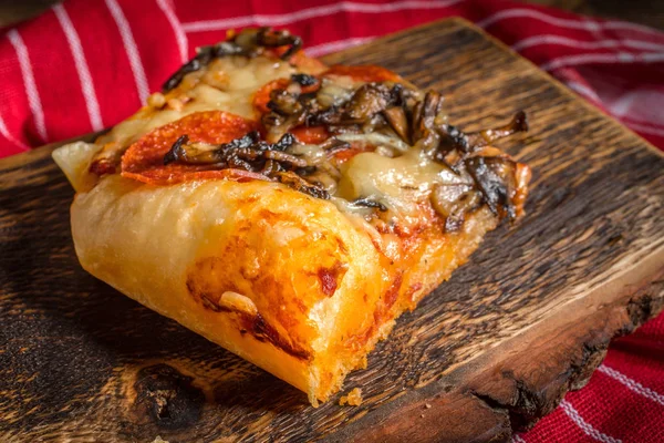 Bir parça kesme tahtası üzerinde ev yapımı pizza.