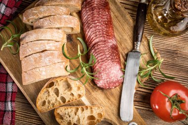 İtalyan ciabatta ekmeği Dilim salam ile Ahşap doğrama tahtası üzerinde kesilmiş.