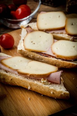 Jambon ve kesme tahtası üzerinde füme peynir sandviç.