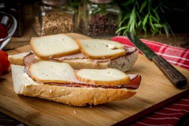 Jambon ve kesme tahtası üzerinde füme peynir sandviç.