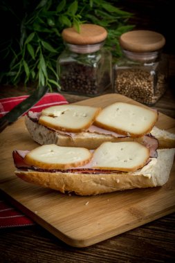 Jambon ve kesme tahtası üzerinde füme peynir sandviç.