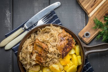 Kızarmış patatesle servis edilen lahana turşulu pirzola. Üst görünüm.