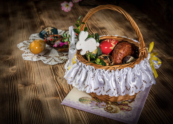 Traditional Easter basket with colored eggs on the wooden table.