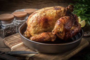 Ahşap masa üzerinde plaka üzerinde kavrulmuş tavuk.