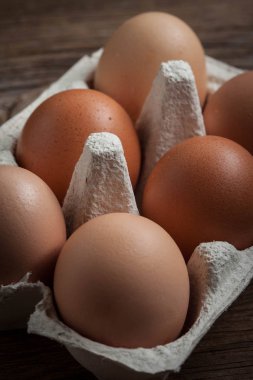 Ahşap rustik arka plan üzerinde taze çiftlik yumurtaları. Karanlık ışık.