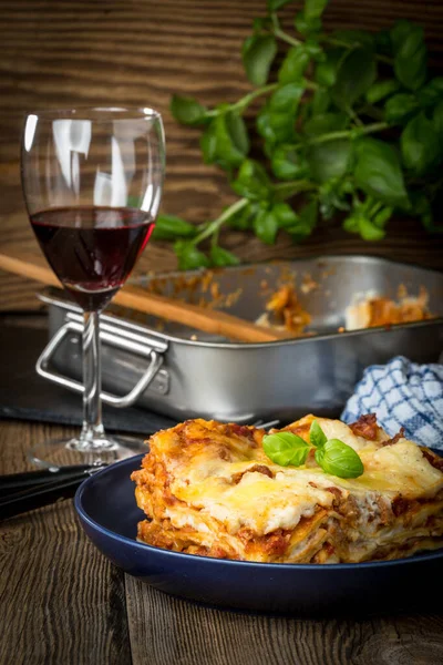 Pezzo di gustose lasagne calde con vino rosso. — Foto Stock