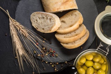 İtalyan ciabatta ekmeği. Koyu arkaplanda taş kesme tahtasına dilimlenmiş..