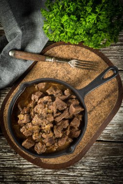 Dökme demir tavada sığır güveci, ahşap arka plan. Yüzeyin derinliği. Üst görünüm.
