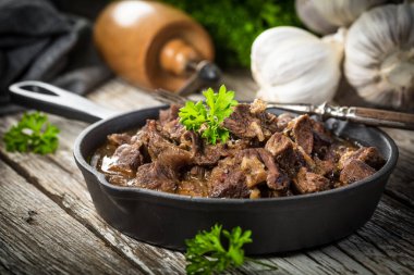 Dökme demir tavada sığır güveci, ahşap arka plan. Sığ alan derinliği.