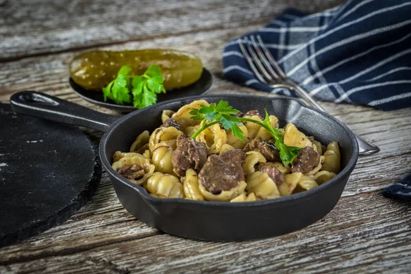 İtalyan makarna kabukları ve biftek sosu ahşap masada dökme demir tavada..