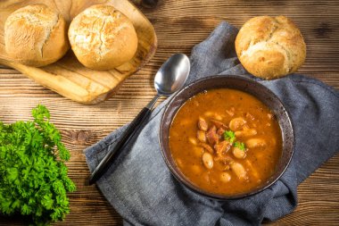 Domates soslu fasulye, pastırma ve siyah kasede sosis. Seçici odak.