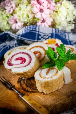 Tahta zemin üzerinde meyve reçeli ile ev yapımı tatlı rulo dilimleri.
