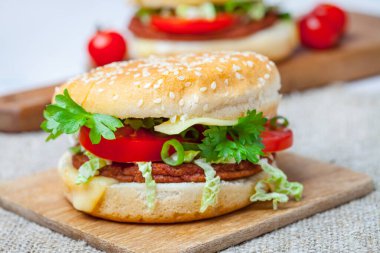 Ahşap tahta üzerinde taze sebze ile ev yapımı hamburger.