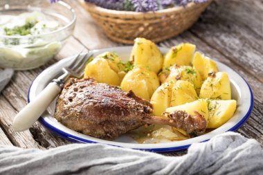 Patates ve salatalık ile servis edilen kızarmış ördek bacağı. Seçici odak.