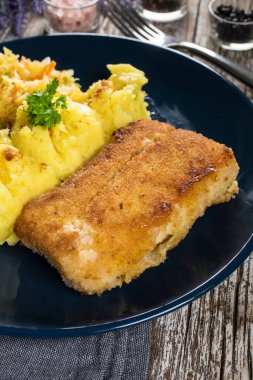 Haşlanmış patates ve sebze salatasıyla servis edilen kızarmış morina filetosu..