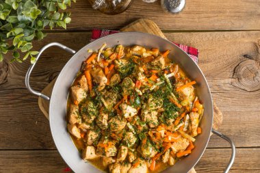 Metal bir tavada sebzeli kızarmış tavuk parçaları. Küçük odak derinliği.