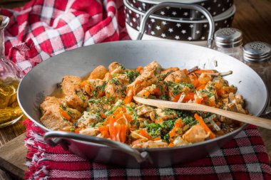 Metal bir tavada sebzeli kızarmış tavuk parçaları. Küçük odak derinliği.