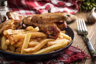 Ahşap masada patates kızartmalı tavuk kanadı.