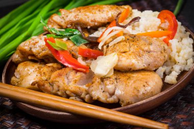 Pirinç ve sebzeyle servis edilen kızarmış tavuk parçaları..