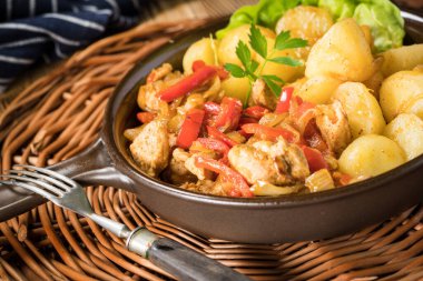 Kırmızı biberli ve soğanlı kızarmış tavuk parçaları, patates ile servis edilir..