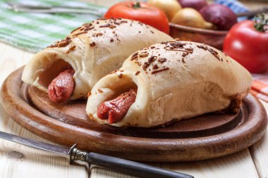 Ahşap bir tahtanın üzerinde hamur içinde pişirilmiş sosis..