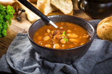 Domates soslu fasulye, pastırma ve siyah kasede sosis. Seçici odak.