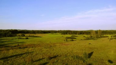 Batan güneşin ışığında çayırlar ve ormanlar.