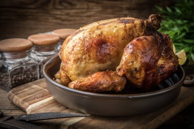 Ahşap masa üzerinde plaka üzerinde kavrulmuş tavuk.