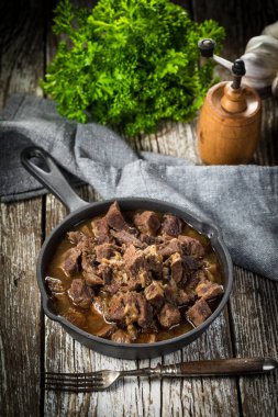 Dökme demir tavada sığır güveci, ahşap arka plan. Sığ alan derinliği.
