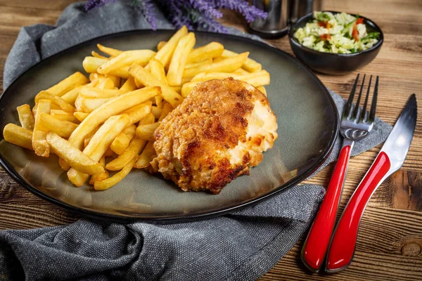 Pastırma ve peynirle doldurulmuş kızarmış tavuk göğsü patates kızartması ve salata ile servis edilir. Küçük alan derinliği.