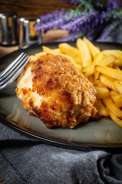 Pastırma ve peynirle doldurulmuş kızarmış tavuk göğsü patates kızartması ve salata ile servis edilir. Küçük alan derinliği.